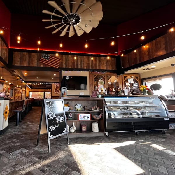 Interior of Rooster Run Cafe with a dessert display, menu board, and rustic decor.